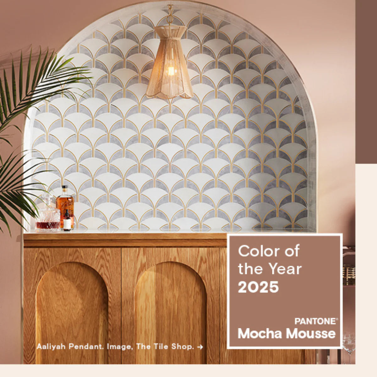 Arched alcove with white-and-gold fan tiles above a wood cabinet, pendant light and decanters, labeled Color of the Year 2025 Mocha Mousse