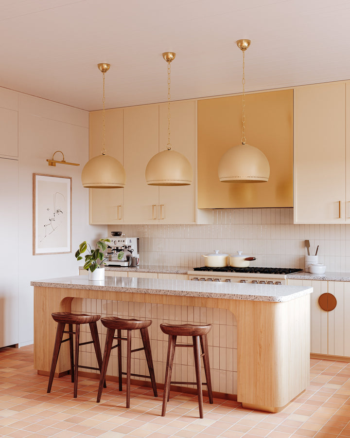Elowen picture light mounted above framed art in a warm-toned kitchen with three dome pendants and a breakfast island