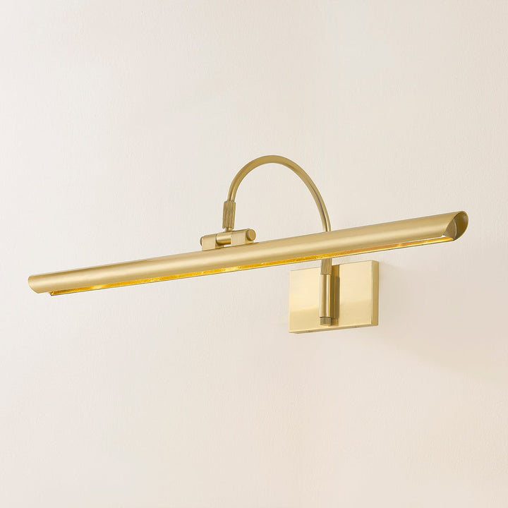 Angled view of Elowen Picture Light showcasing a long slim LED shade and curved arm in antique gold finish against pale wall