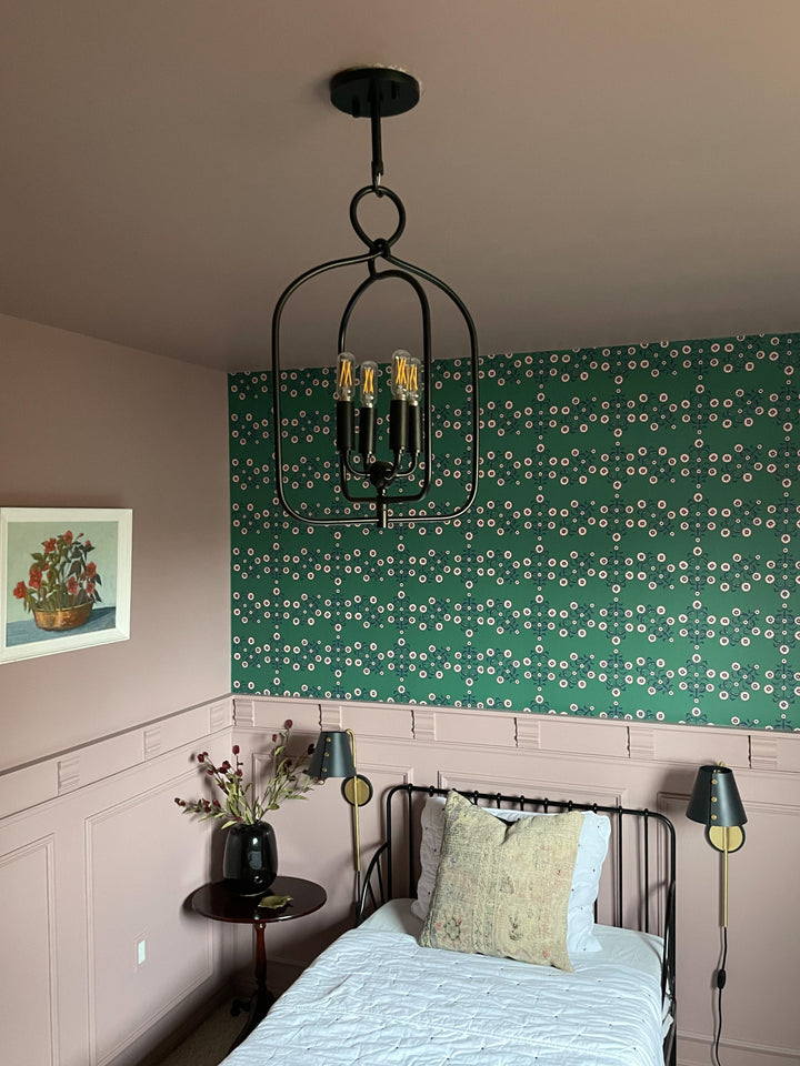 Mallory pendant hanging from the ceiling, black metal cage with three filament bulbs in a pink bedroom with green floral wallpaper